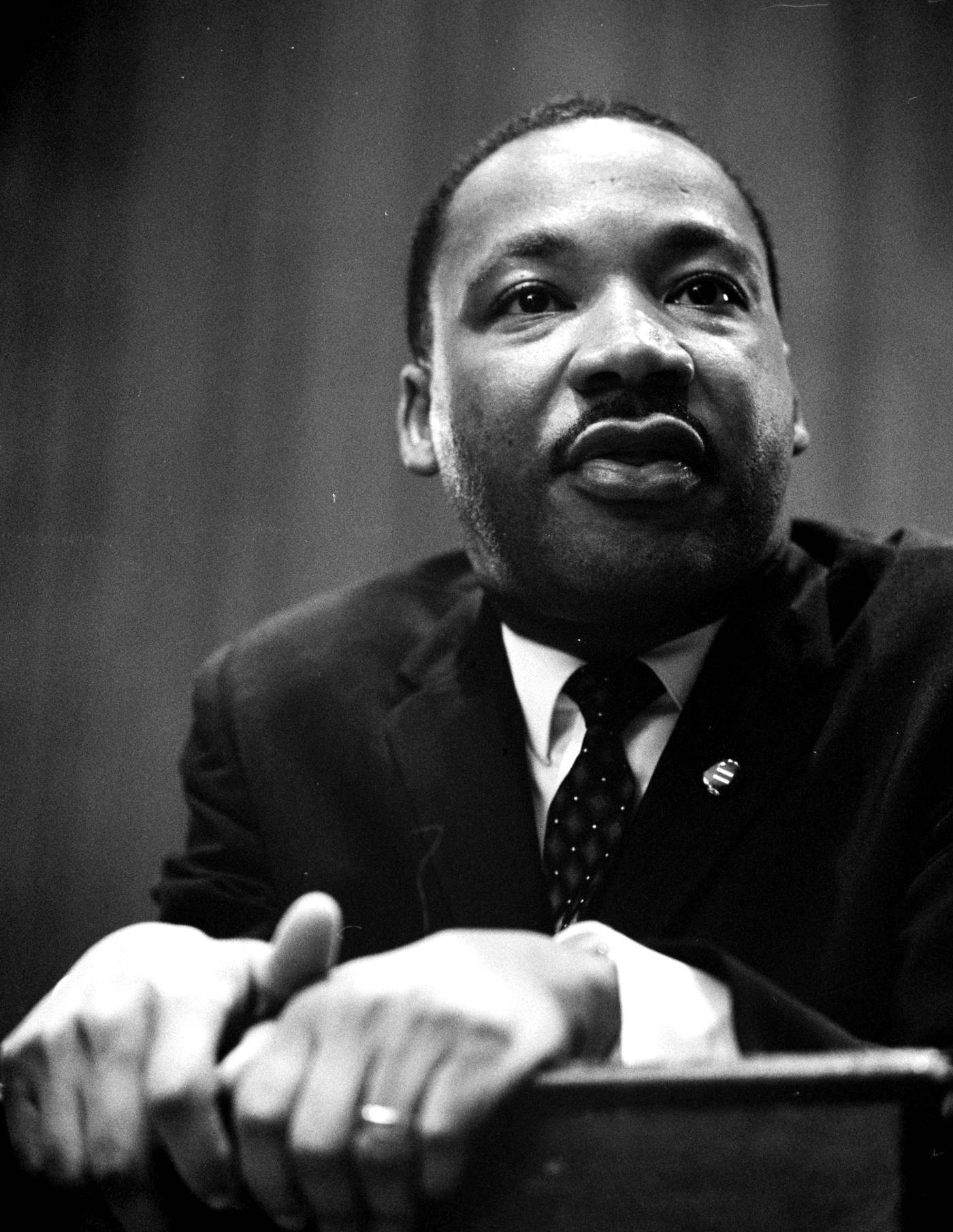 Martin Luther King Jr. en 1964, portrait en noir et blanc, accoudé à un pupitre